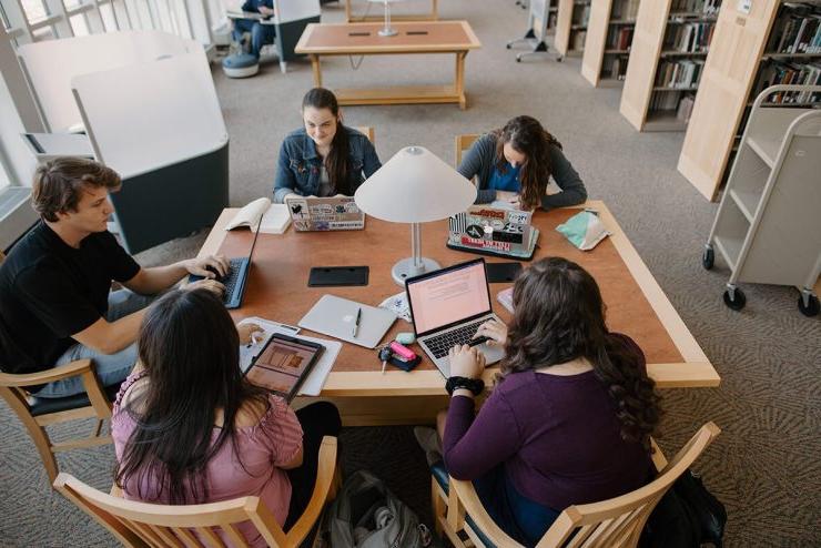 五个电子游艺信誉排行的学生围坐在图书馆的桌子旁，拿出了他们的笔记本电脑